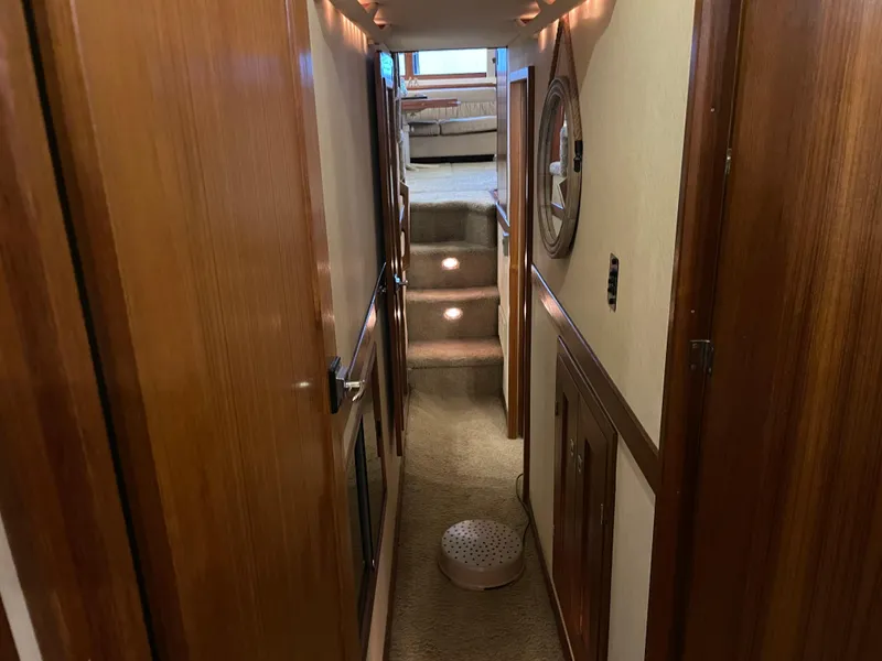 Slide: The Image of Hallway inside 1995 Bayliner 4788 Pilot House Motoryacht, featuring wooden paneling and carpeted stairs. - 48