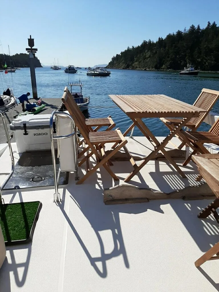 Slide: The Image of 1995 Bayliner 4788 Pilot House Motoryacht deck with wooden furniture, overlooking serene waters. - 9