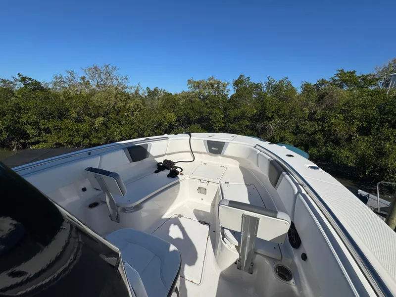 Slide: The Image of 2023 Robalo R270 Center Console boat with spacious seating, surrounded by lush greenery. - 15