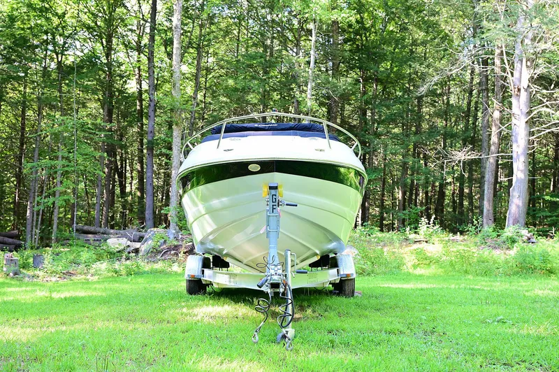 Slide: The Image of 2015 Crownline 236 boat on trailer in a lush forest setting. - 1