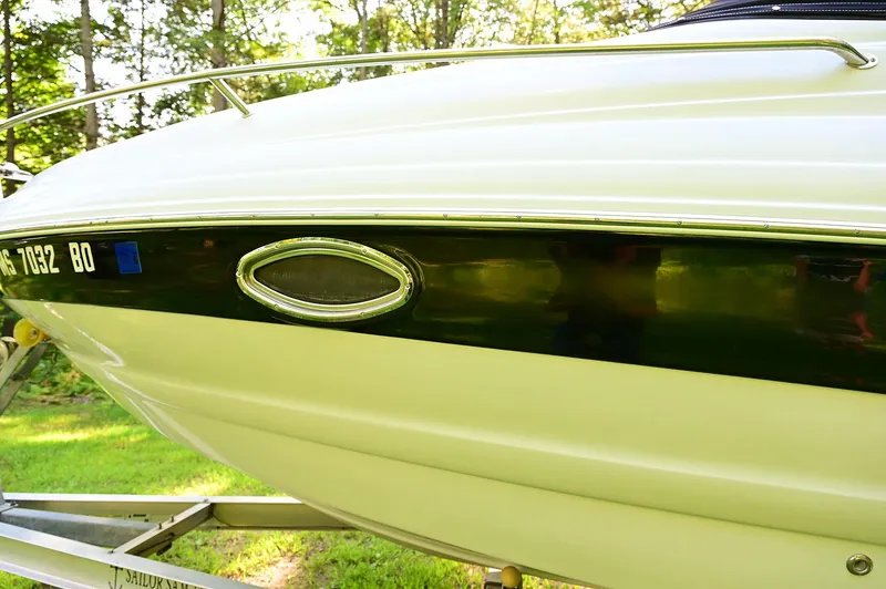 Slide: The Image of 2015 Crownline 236 boat side view on trailer, surrounded by greenery. - 18