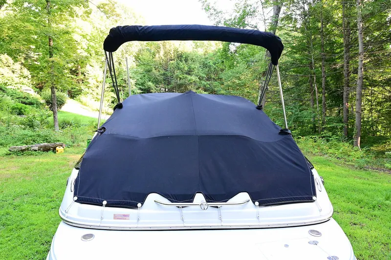 Slide: The Image of 2015 Crownline 236 boat with cover in a lush green setting. - 23