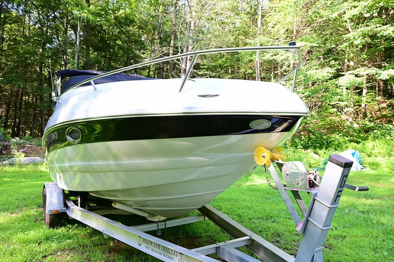Slide: The Image of 2015 Crownline 236 boat on trailer, surrounded by lush greenery. - 3
