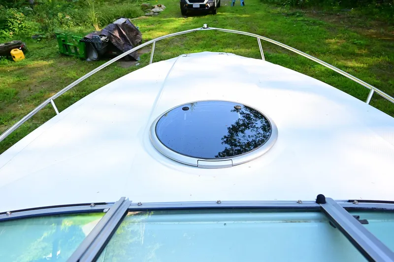 Slide: The Image of 2015 Crownline 236 boat deck with circular hatch, surrounded by greenery. - 32
