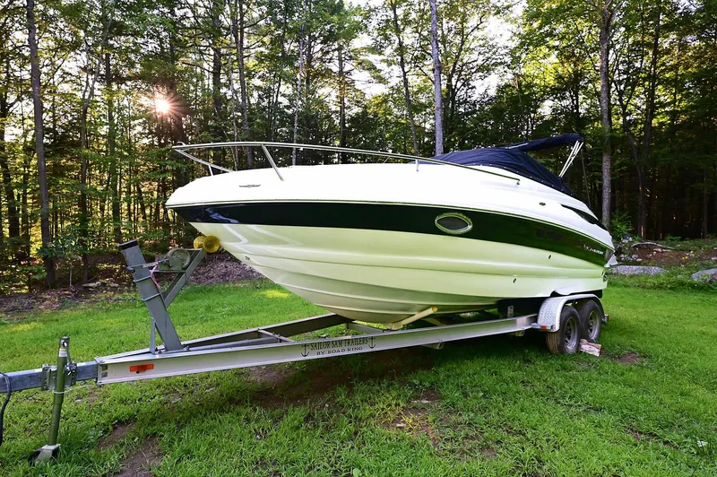 Slide: The Image of 2015 Crownline 236 boat on trailer in a grassy area with trees in the background. - 4