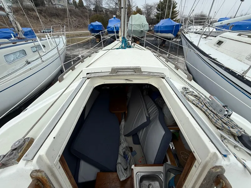 The Image of 1976 Pearson P-30 sailboat with open cabin, docked among other boats. - 1