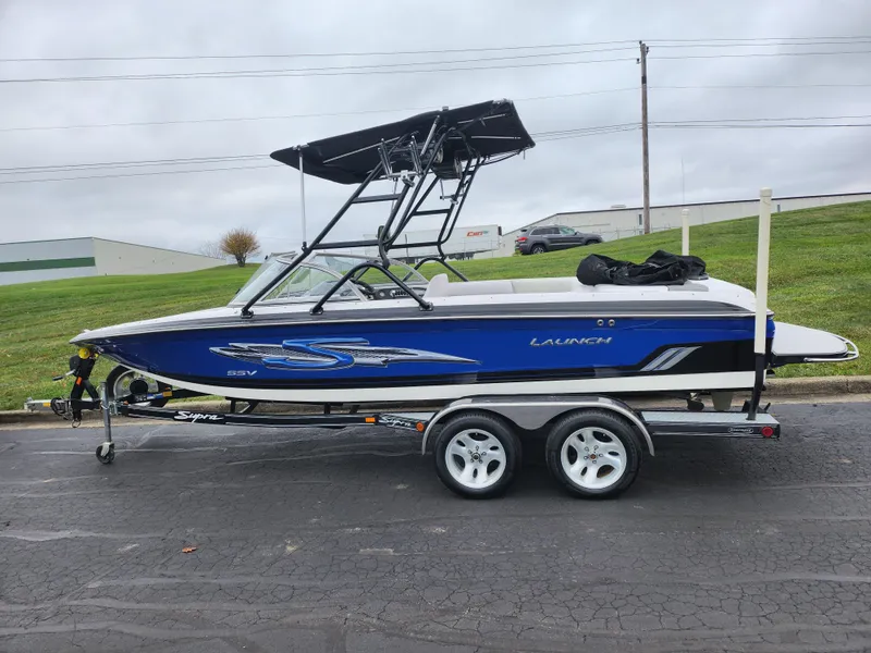 Slide: The Image of 2004 Supra Launch SSV boat on trailer, blue and white design, parked outdoors. - 4