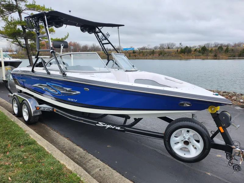Slide: The Image of 2004 Supra Launch SSV boat on trailer by lakeside, blue and white design. - 8