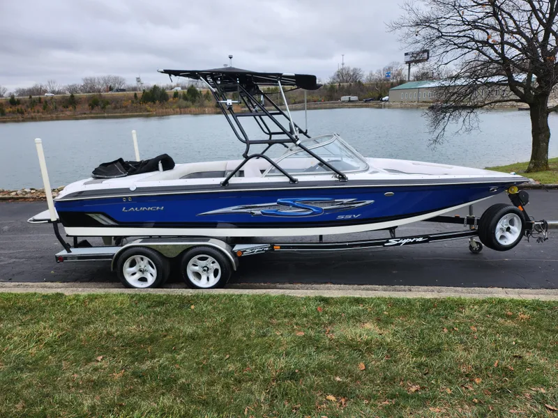 Slide: The Image of 2004 Supra Launch SSV boat on trailer by a lake. - 9