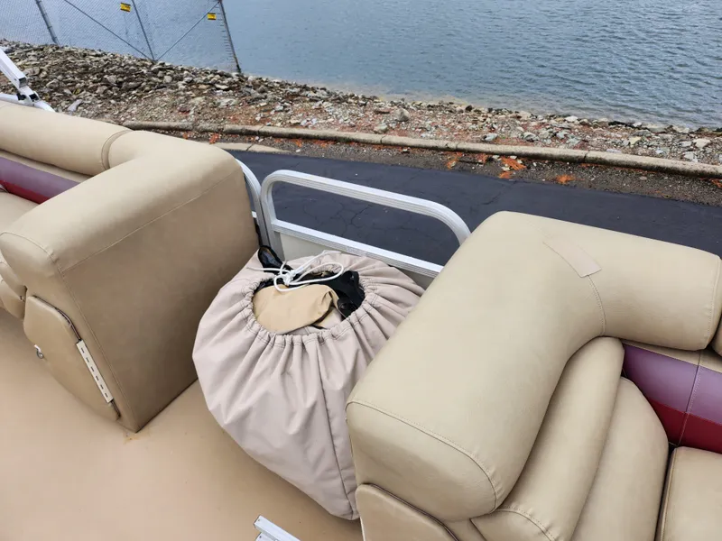 Slide: The Image of Bennington 2580LX boat interior with beige seating, near a waterfront, year 2000 model. - 12