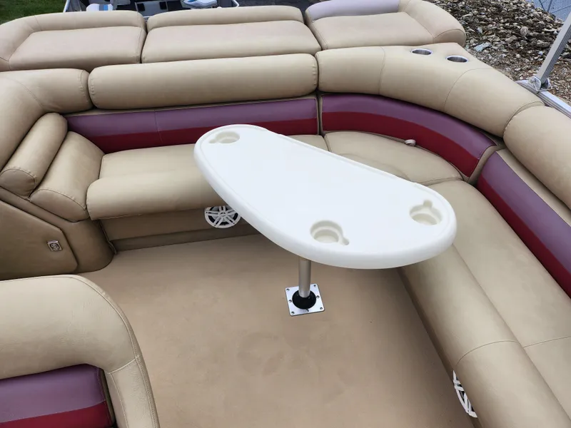 Slide: The Image of Bennington 2580LX 2000 boat interior with beige and maroon seating, featuring a white table. - 16