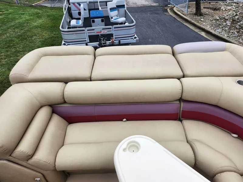Slide: The Image of Bennington 2580LX 2000 pontoon boat with beige and red seating, docked on a paved area. - 17