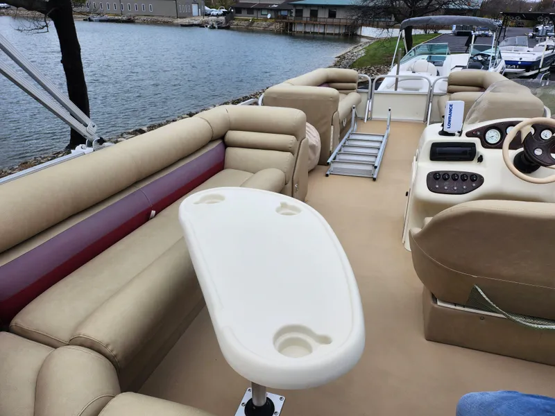 Slide: The Image of Bennington 2580LX 2000 pontoon boat interior with seating and table, docked by a lake. - 19