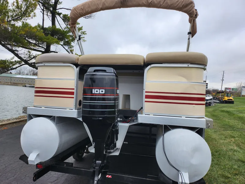 Slide: The Image of 2000 Bennington 2580LX pontoon boat with 100 HP outboard motor, docked by a lake. - 2