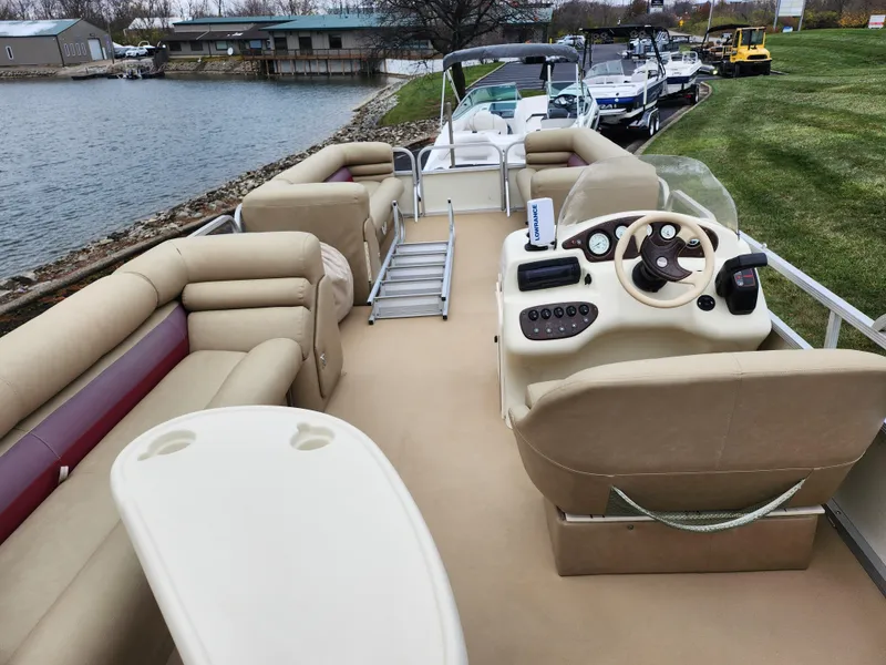 Slide: The Image of Bennington 2580LX pontoon boat, 2000 model, with beige seating and steering console, docked by a lake. - 20