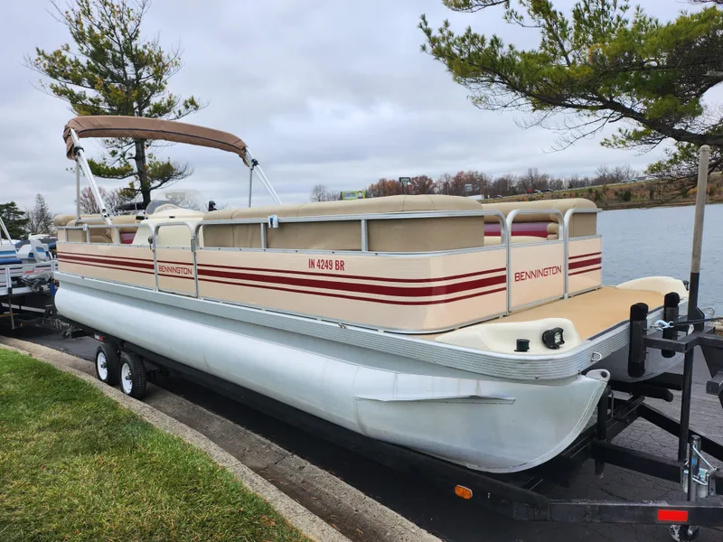 Slide: The Image of 2000 Bennington 2580LX pontoon boat on trailer by a lake. - 8