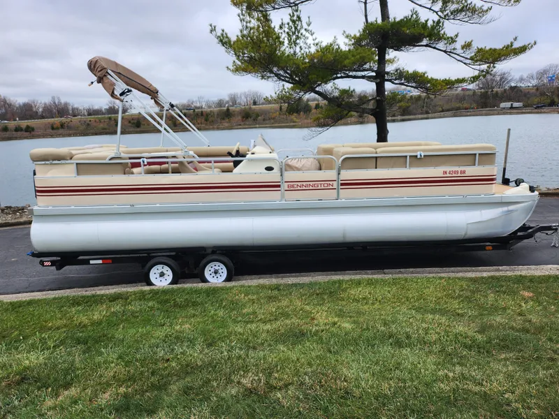 Slide: The Image of 2000 Bennington 2580LX pontoon boat on trailer by a lake. - 9