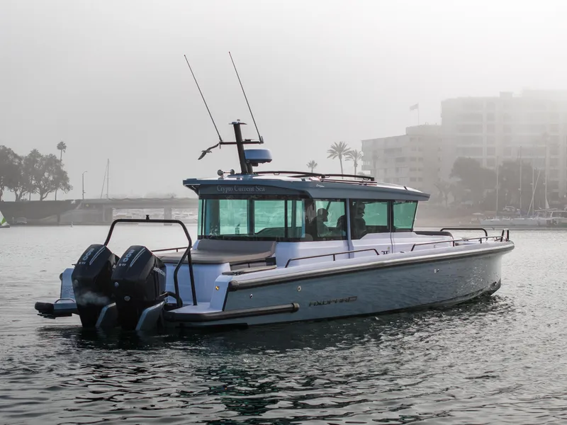 Slide: The Image of 2023 Axopar 37 Aft Cabin boat on misty water with cityscape background. - 13
