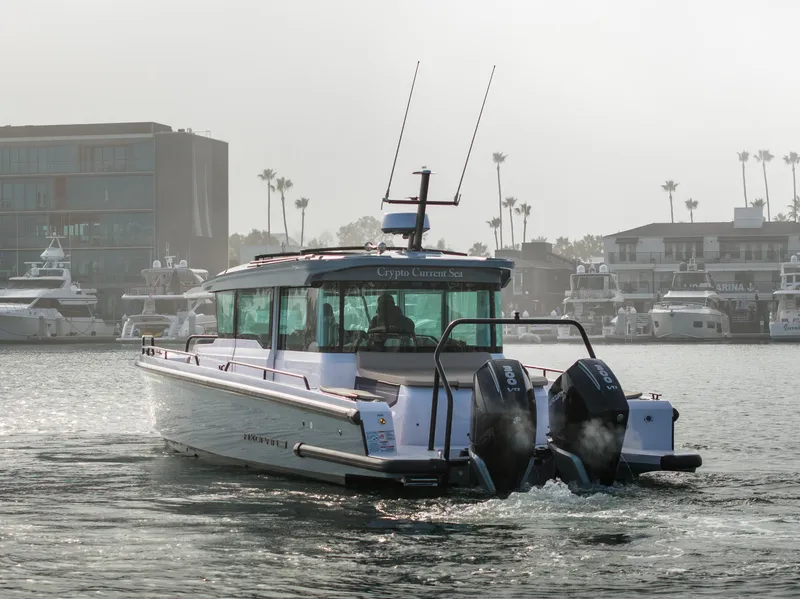 Slide: The Image of 2023 Axopar 37 Aft Cabin boat cruising in a marina with yachts and buildings. - 16