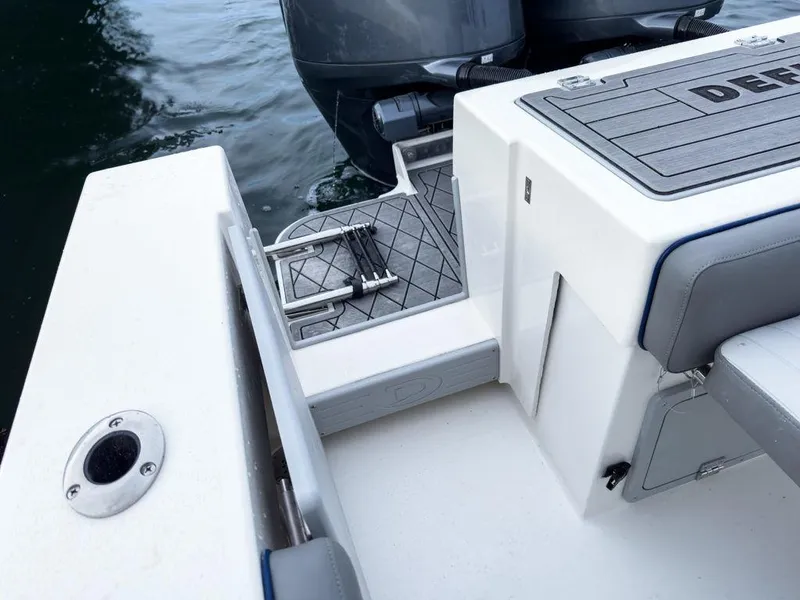 Slide: The Image of 2025 Defiance 260 Admiral boat deck with seating and motor, on calm water. - 12