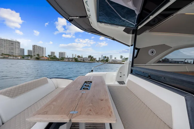 Slide: The Image of 2018 Jeanneau Leader 46 yacht with elegant seating and table, city skyline in background. - 24