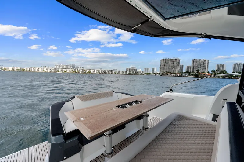 Slide: The Image of 2018 Jeanneau Leader 46 yacht with elegant seating and table, overlooking a city skyline. - 25