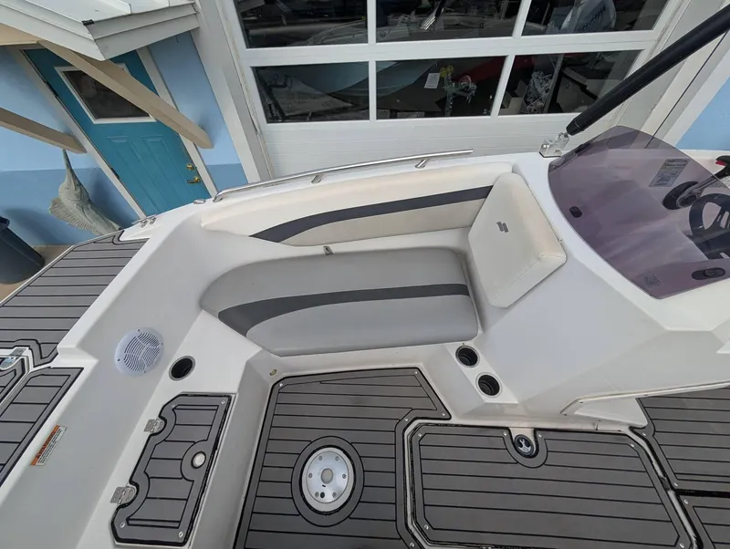 Slide: The Image of 2020 Starcraft SVX 171 boat interior with gray seating and deck, near a blue building. - 6