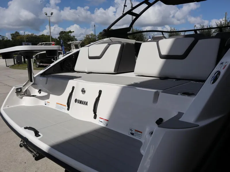 Slide: The Image of 2025 Yamaha AR250 boat interior with seating and table, under a partly cloudy sky. - 12