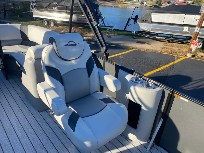 Slide: The Image of Luxurious SunCatcher Select 322RC 2025 boat seat with cup holders, docked by the water. - 9