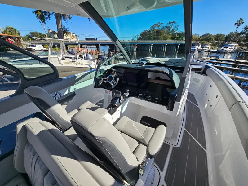 Slide: The Image of 2025 Monterey Elite 30 OB boat interior with modern dashboard and seating, docked by a marina. - 31