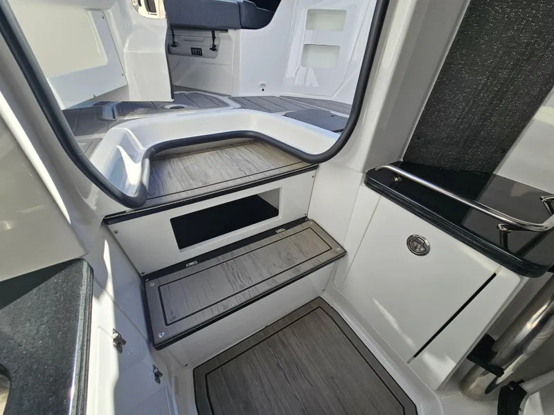 Slide: The Image of 2025 Monterey Elite 30 OB boat interior with sleek, modern design and wood-accented steps. - 46