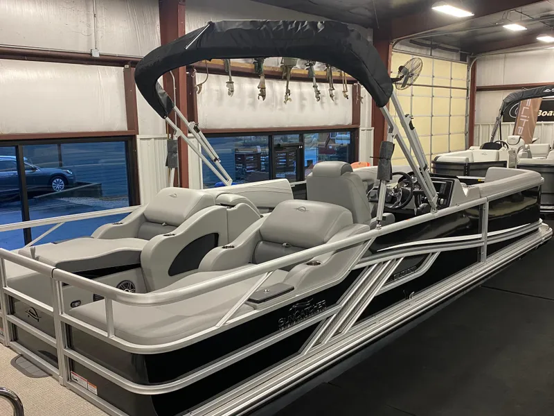 Slide: The Image of 2025 SunCatcher Fusion 324SS pontoon boat in showroom, featuring sleek design and comfortable seating. - 2