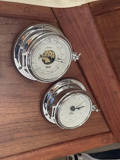 Slide: The Image of Nautical instruments on 1987 Pacific Seacraft PS37, featuring a barometer and clock on wooden panel. - 11