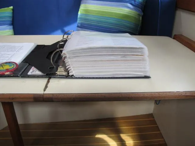 Slide: The Image of Thick binder on table inside 1987 Pacific Seacraft PS37 sailboat cabin. - 44