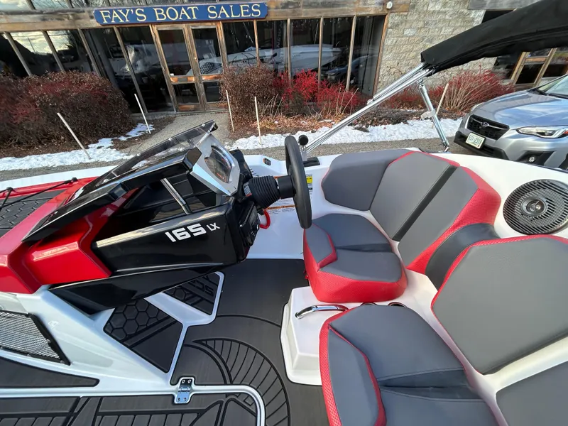 Slide: The Image of 2025 Scarab 165 LX boat interior with red and gray seating at Fay's Boat Sales. - 15