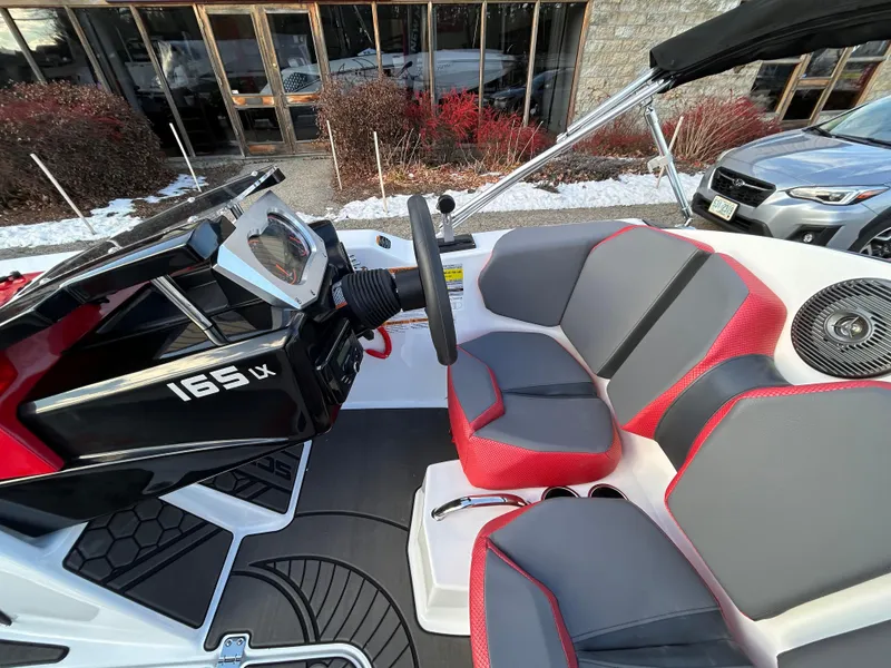Slide: The Image of 2025 Scarab 165 LX boat interior with red and gray seating, steering wheel, and dashboard. - 19