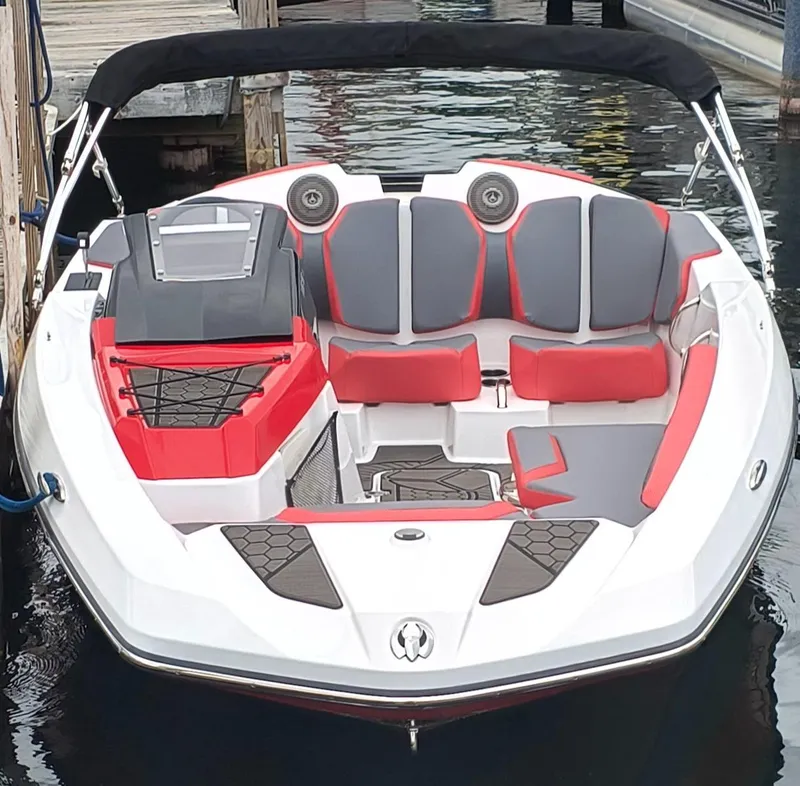 Slide: The Image of 2025 Scarab 165 LX boat with red and gray seating, docked on calm water. - 3