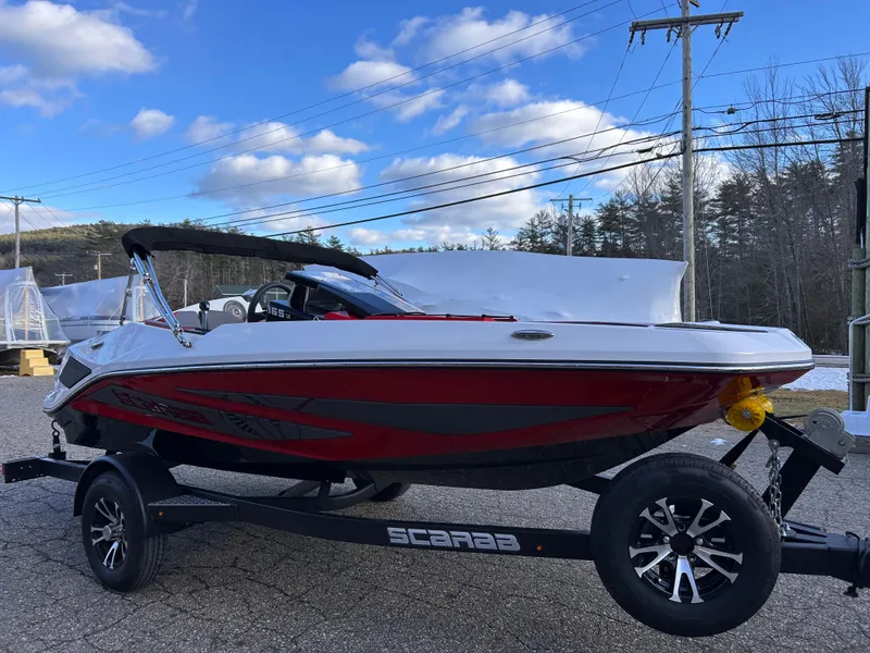 Slide: The Image of 2025 Scarab 165 LX boat on trailer, red and white design, parked outdoors. - 8