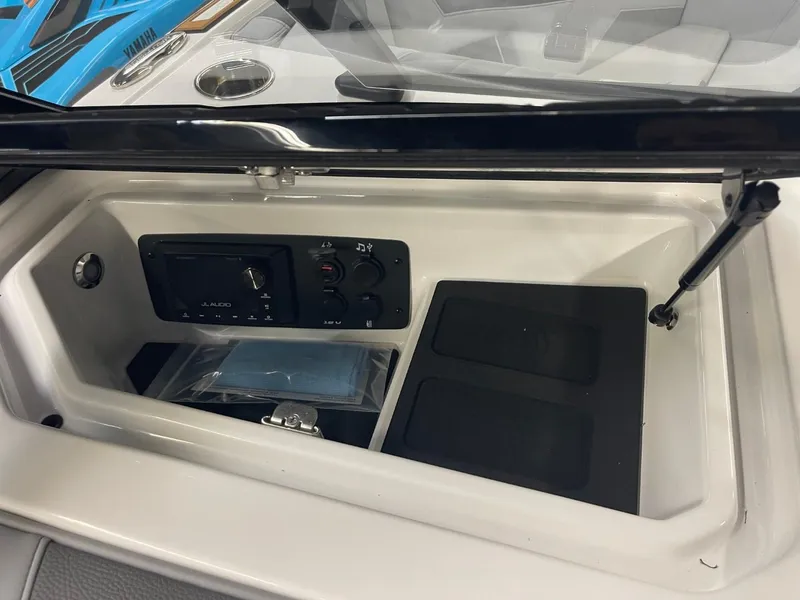 Slide: The Image of 2025 Nautique Super Air Nautique S21 dashboard compartment with controls and storage. - 32