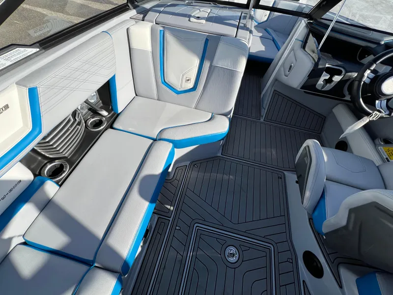Slide: The Image of 2020 Nautique G21 boat interior with gray and blue seating, cup holders, and steering wheel. - 20