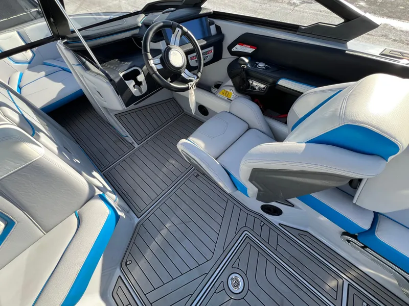 Slide: The Image of 2020 Nautique G21 boat interior with sleek design, featuring gray and blue seating and modern dashboard. - 21