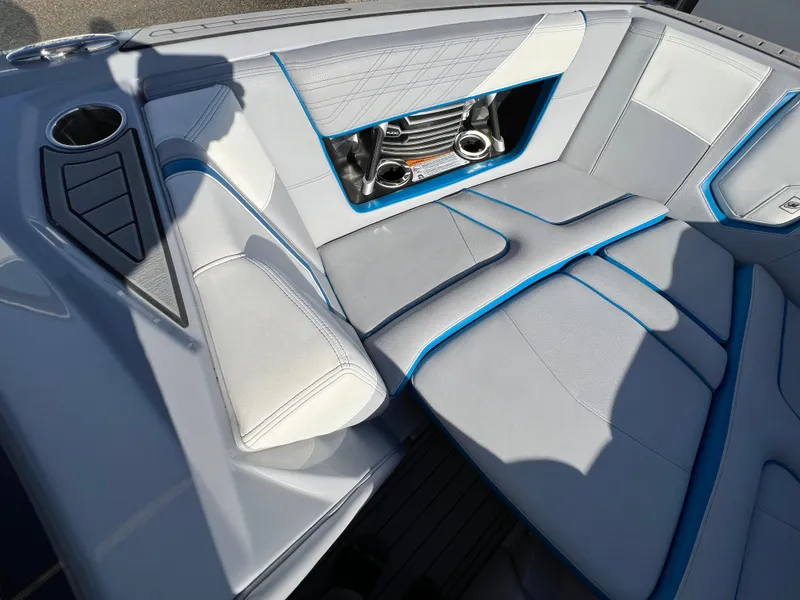 Slide: The Image of 2020 Nautique G21 boat interior with gray and blue seating, cup holder, and speaker system. - 26