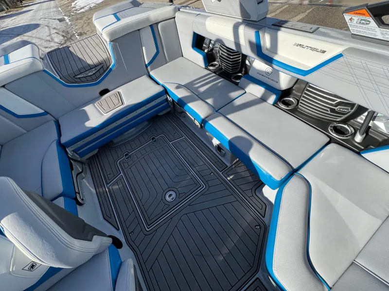Slide: The Image of 2020 Nautique G21 boat interior with gray and blue seating, cup holders, and non-slip flooring. - 33