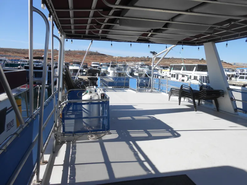 Slide: The Image of 1998 Lakeview 5516 houseboat deck with chairs and propane tanks, docked in a marina. - 27