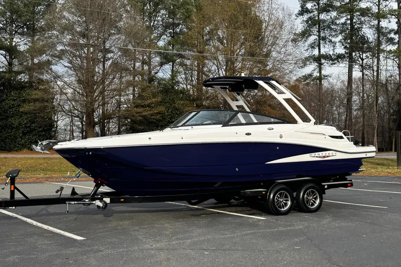 Slide: The Image of 2025 Monterey M6 boat on trailer in a parking lot, surrounded by trees. - 6