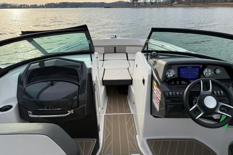 Slide: The Image of 2025 Monterey M6 boat interior with modern dashboard and seating, overlooking a serene lake. - 9