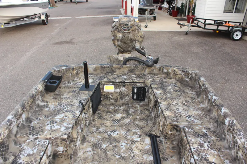 Slide: The Image of 2025 Excel 1860 F4 Shallow Water boat with camouflage design in a parking area. - 10