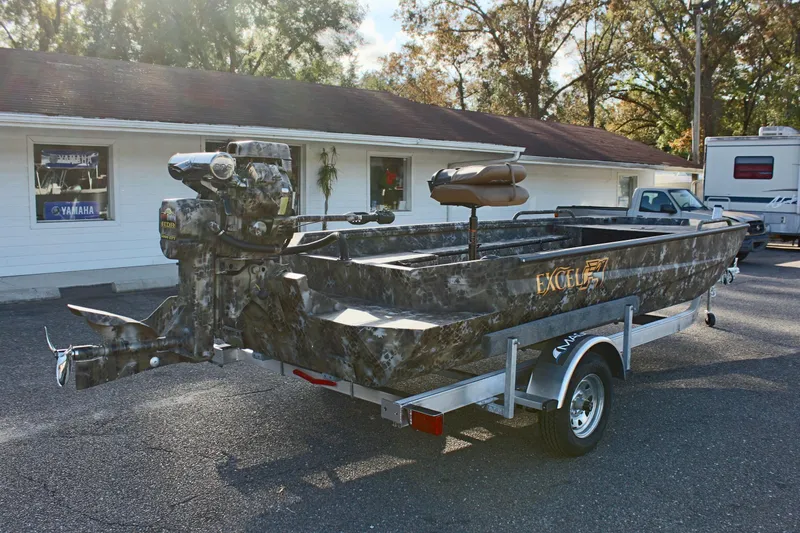 Slide: The Image of 2025 Excel 1860 F4 Shallow Water boat on trailer, camo design, parked outdoors. - 5