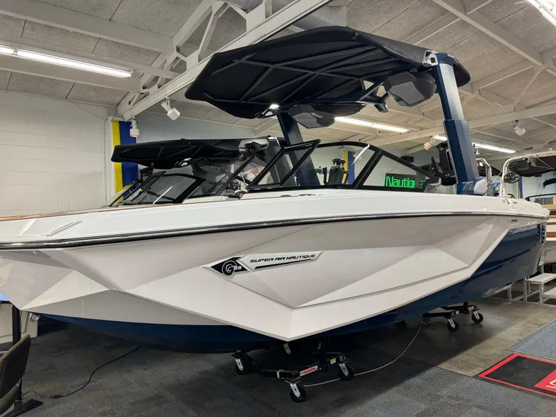 Slide: The Image of 2024 Nautique Super Air Nautique G23 boat in showroom, white and blue design. - 14