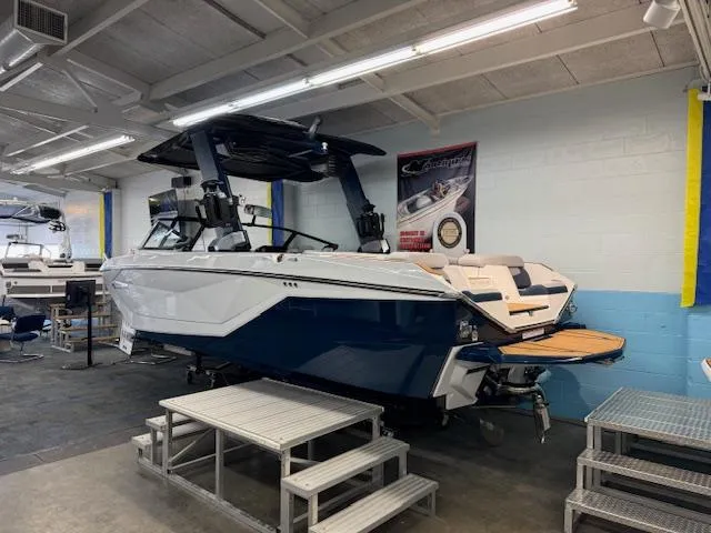 Slide: The Image of 2024 Nautique Super Air Nautique G23 boat in showroom, blue and white exterior. - 6